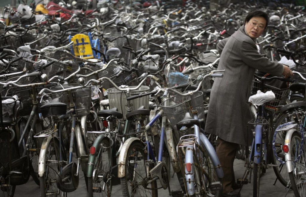 a-woman-collects-her-bicycle-from-a-parking-lot-outside-of-a-subway-station-in-beijing